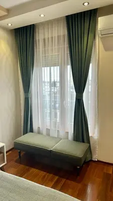 a bed sitting in front of a window with curtains at Gorica Hill Luxury Residence in Podgorica