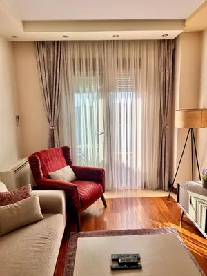 a living room with a couch and a red chair at Gorica Hill Luxury Residence in Podgorica