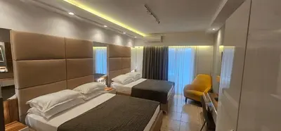 a hotel room with two beds and a chair at Resort Comfort - Long Beach in Ulcinj