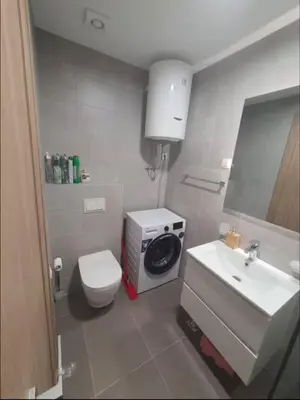 a bathroom with a toilet and a sink and a washing machine at Master Quart studio apartment in Podgorica