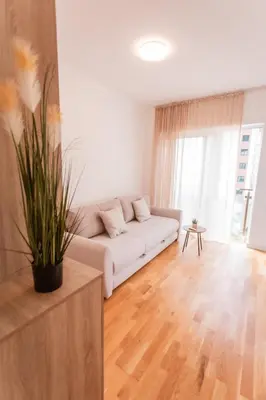 a living room with a white couch and a wooden floor at Maris View in Becici
