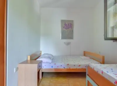 a small bedroom with two beds and a table at Villa Marković 2 in Sutomore