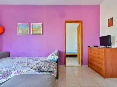 a bedroom with a purple wall with a bed and a dresser at Villa Marković 2 in Sutomore