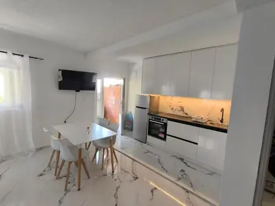 a kitchen with white cabinets and a table and chairs at Nar in Budva