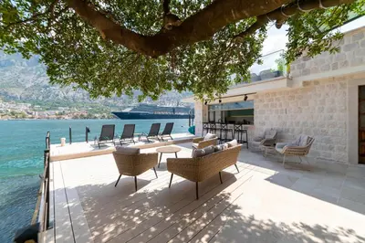 a patio with chairs and tables and a view of the water at Seafront Kotor Bay View Villa NW in Muo