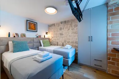 a bedroom with two beds and a brick wall at Seafront Kotor Bay View Villa NW in Muo