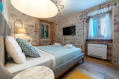 a bedroom with a bed in a brick wall at Seafront Kotor Bay View Villa NW in Muo