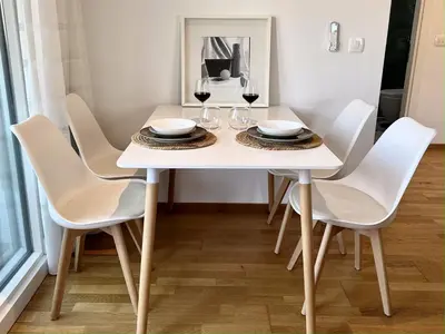 a white dining room table with chairs and wine glasses at Alula Apartments in Bar