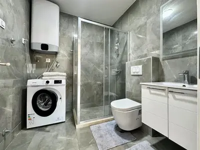 a bathroom with a washing machine and a toilet at Alula Apartments in Bar