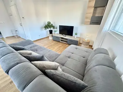 a living room with a large couch in front of a tv at Alula Apartments in Bar