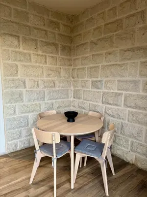 a wooden table and chairs in a room with a brick wall at Sunny Villas Luxury Apartment with Garden and Seaview in Katun