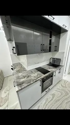 a kitchen with white cabinets and marble counter tops at Garsonjera studio in Bar