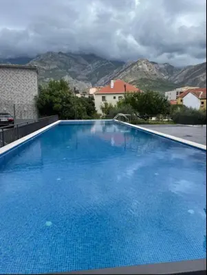 a large blue swimming pool with mountains in the background at Garsonjera studio in Bar
