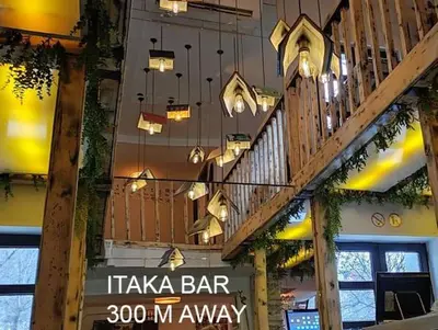 a restaurant with a bar with lights hanging from the ceiling at Parkside Place in Podgorica