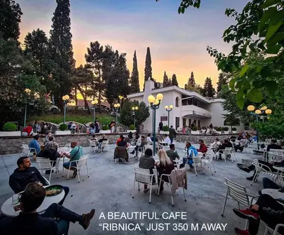 a group of people sitting in chairs in front of a building at Parkside Place in Podgorica