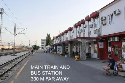 a train station with a man sitting on a bench next to the tracks at Parkside Place in Podgorica