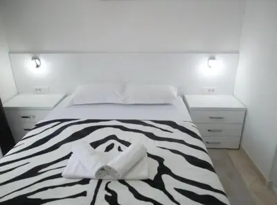 a bedroom with a black and white bed with two towels at Guest House 4M Gregović in Petrovac na Moru