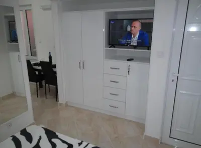 a living room with a tv in a white cabinet at Guest House 4M Gregović in Petrovac na Moru