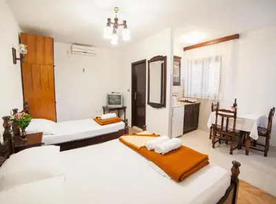 a bedroom with two beds and a dining room at Guest House 4M Gregović in Petrovac na Moru