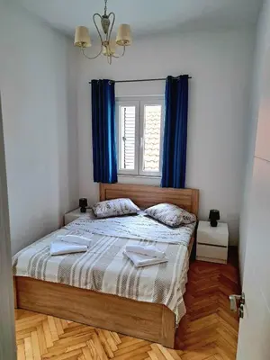 a bedroom with a bed with blue curtains and a window at Old town nest in Budva