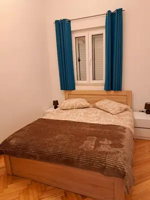 a bedroom with a bed with blue curtains and a window at Old town nest in Budva
