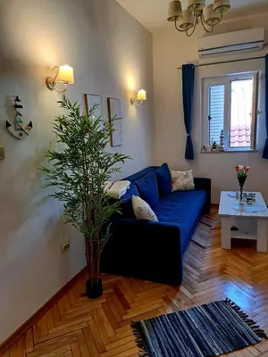 a living room with a blue couch and a plant at Old town nest in Budva