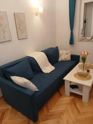 a blue couch in a living room with a table at Old town nest in Budva