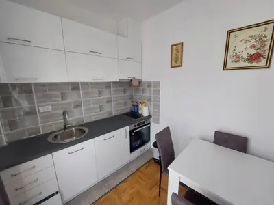 a kitchen with white cabinets and a sink and a table at Luxury Andrej Apartment with Garage in Polje