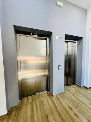 two elevator doors in an empty room with wood floors at BAR - Jednosoban stan u centru in Bar