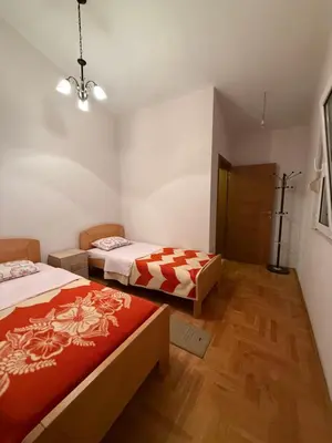 a bedroom with two beds and a wooden floor at Vila Žuta in Bar