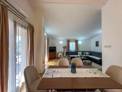 a living room with a wooden table and chairs at City Big Apartman in Podgorica
