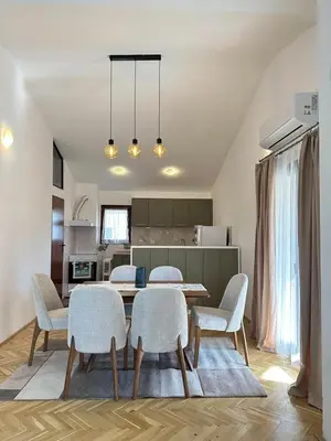 a dining room with a table and chairs and a kitchen at City Big Apartman in Podgorica