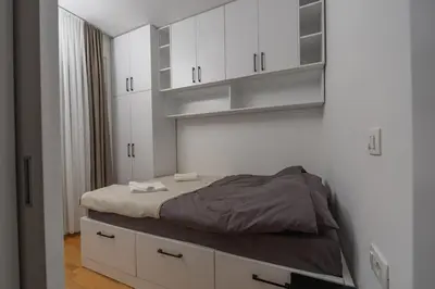 a bedroom with a bed and white cabinets at Deluxe Apartment Zarah in Bar