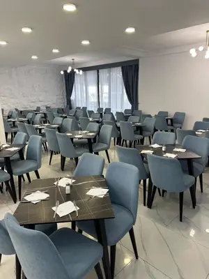 a dining room with tables and blue chairs at Hotel SPICH Biserna Obala Čanj in Čanj