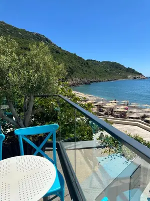 a blue chair and a table on a balcony with a beach at Hotel SPICH Biserna Obala Čanj in Čanj