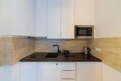 a kitchen with white cabinets and a sink and a microwave at Lamadu Residence in Sutomore
