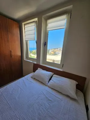 a bedroom with a large bed with two windows at 50 Shades of Blue in Ulcinj