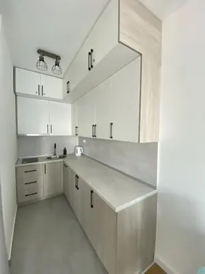 a kitchen with white cabinets and a large mirror at AZZURRO BAR Apartment in Bar