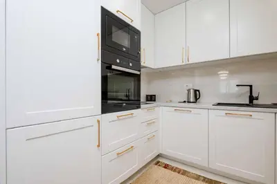 a white kitchen with white cabinets and a black microwave at Sunny View in Bar