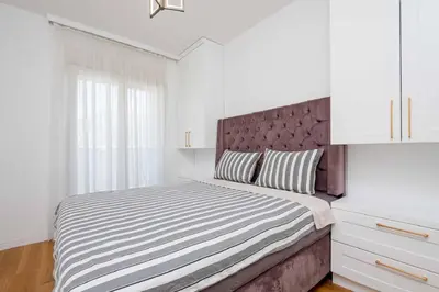 a white bedroom with a large bed with a headboard at Sunny View in Bar