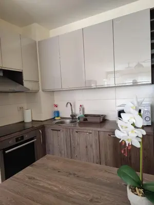 a kitchen with white cabinets and a table with a flower at Apartman City kvart Podgorica 2 in Podgorica
