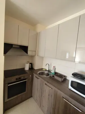 a kitchen with white cabinets and a sink and a microwave at Apartman City kvart Podgorica 2 in Podgorica
