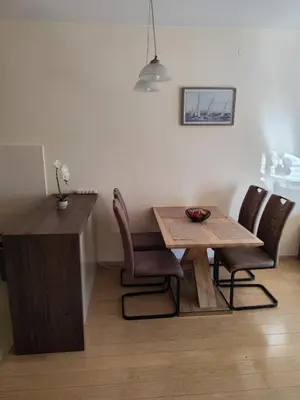 a dining table and chairs in a kitchen with a table and a counter at Apartman City kvart Podgorica 2 in Podgorica
