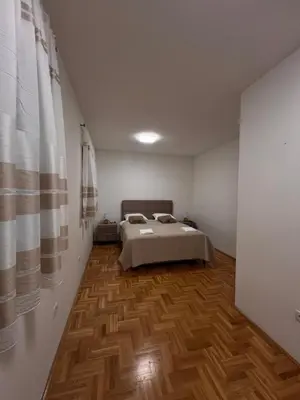 a bedroom with a bed and a wooden floor at Apartman Luka in Cetinje