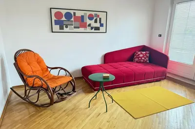 a living room with a red couch and a chair at Cozy central spot in Podgorica