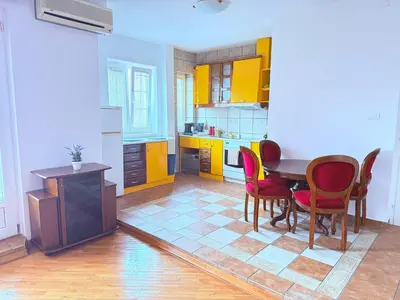 a kitchen with a table and chairs and yellow cabinets at Cozy central spot in Podgorica