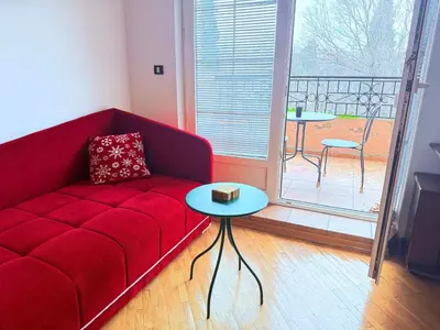 a living room with a red couch and a balcony at Cozy central spot in Podgorica
