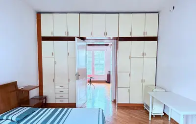 a bedroom with white cabinets and a bed and a desk at Cozy central spot in Podgorica