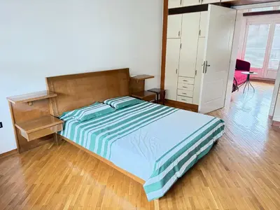 a bedroom with a bed with a wooden headboard and a cabinet at Cozy central spot in Podgorica