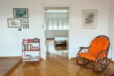 an orange chair in a room with a bedroom at Cozy central spot in Podgorica